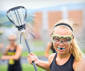 Teen girl playing lacrosse with blue sportsguard