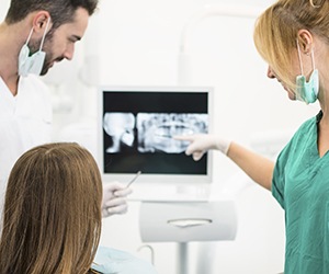 Dentist assistant and patient looking at dental x-rays
